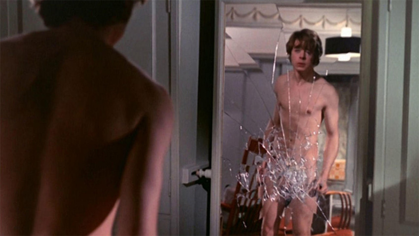 Hywell Bennet naked in front of a shattered mirrror.